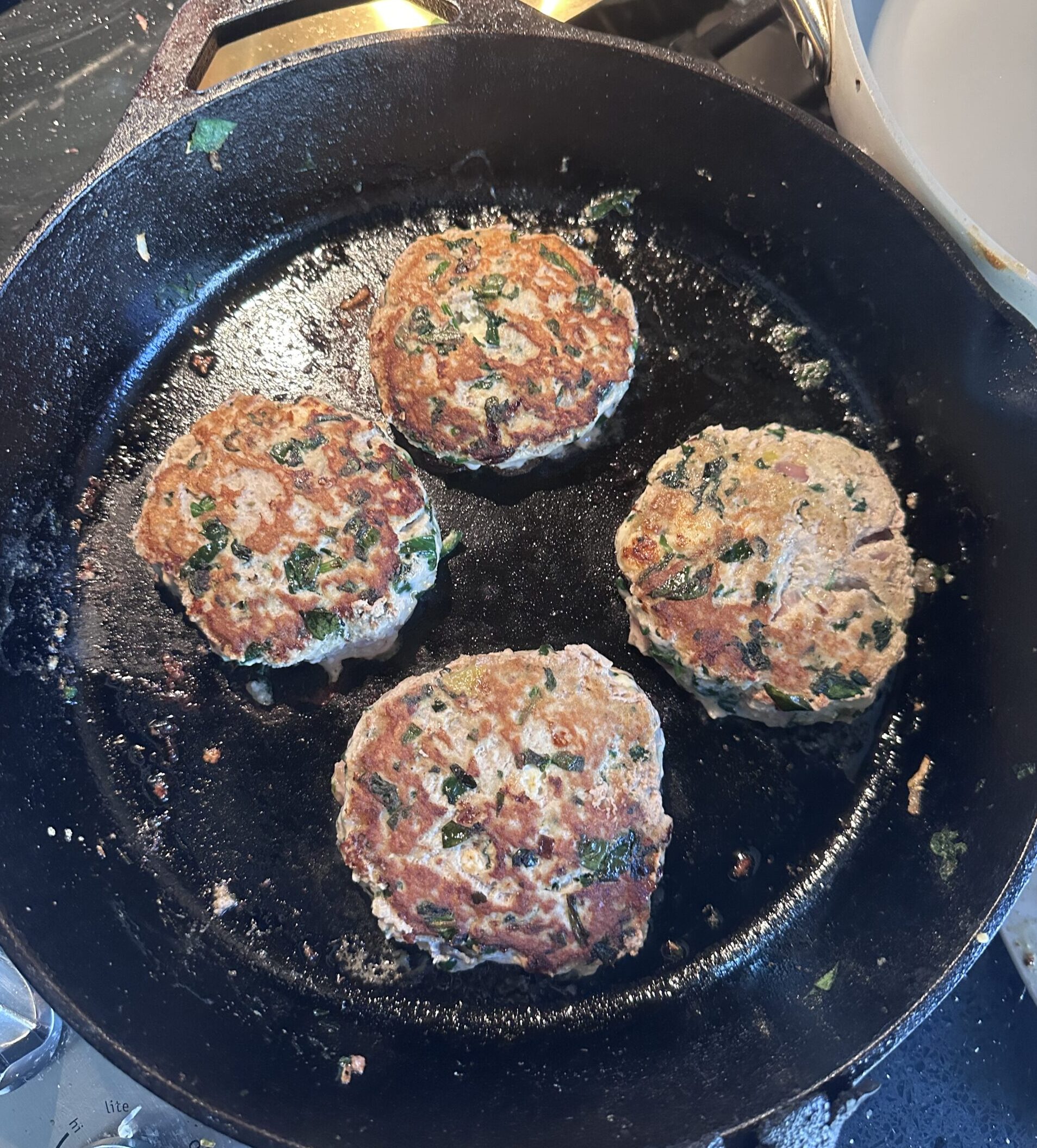 Healthy spinach and feta turkey burgers grilled in a cast iron pan